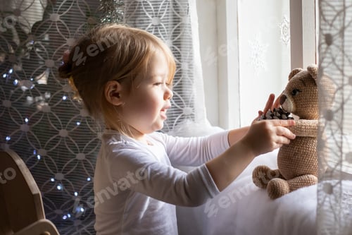 Preview: a little girl and her toy teddy bear near the window