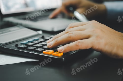 Preview: Closeup of a businessman's hand and a calculator.