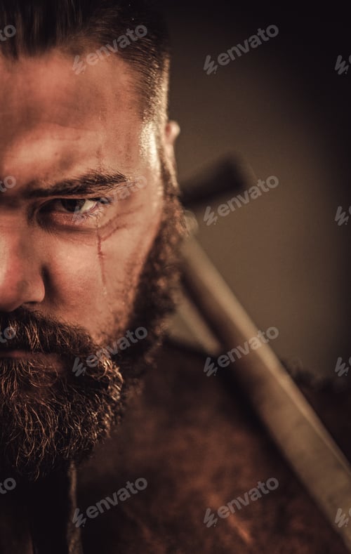Preview: Angry viking with ax in a traditional warrior clothes, posing on a dark background.