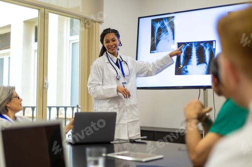 Preview: Female doctor presenting medical x rays to colleagues