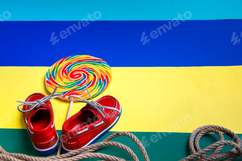 Preview: Small red boat shoes near big multi-colored lollipop