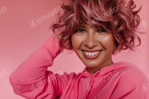 Preview: Tanned cool girl in pink hoodie smiles on isolated background. Close-up inside portrait of pretty c