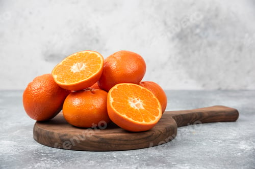 Preview: A wooden board full of juicy orange fruits with slices on stone background