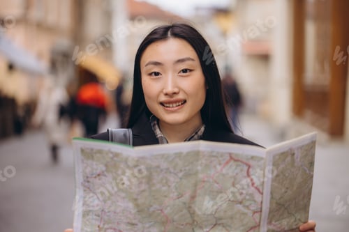 Preview: Portrait of a beautiful Korean woman holding a map on the streets of an old European city