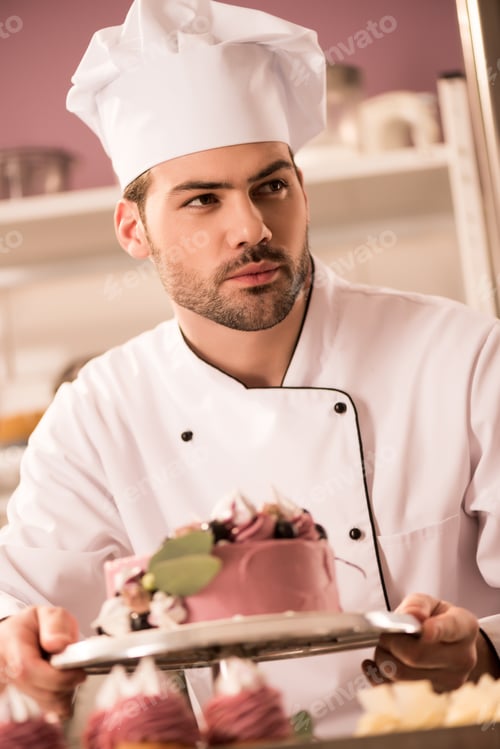 Preview: portrait of confectioner with cake in hands looking away in restaurant kitchen