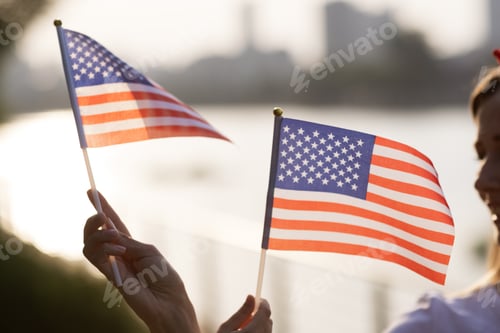 Preview: Patriotic holiday. Happy family, mother and daughter with American flag outdoors on sunset. USA