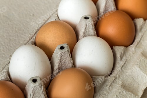 Preview: Hen eggs in open cardboard egg carton on kitchen table light copy space background.