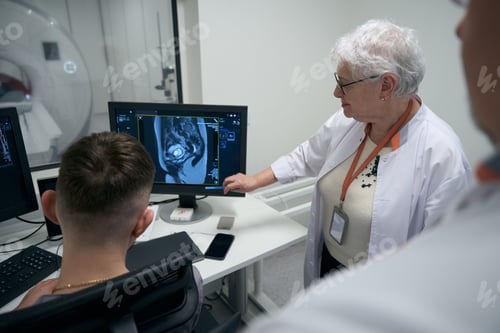 Preview: Colleagues diagnosticians, an elderly woman and men, perform MRI procedure