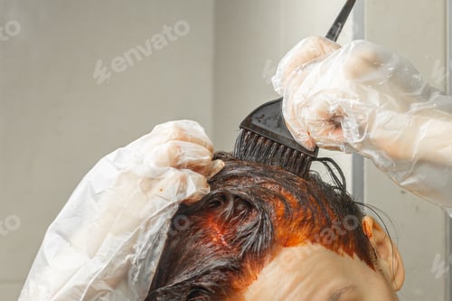 Preview: Process of hair dyeing in red colour using a brush. Young woman apply a red colour to her hair
