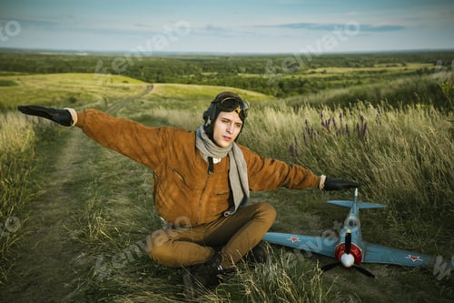 Preview: Guy in vintage clothes pilot with an airplane model outdoors