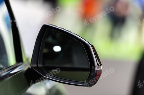 Preview: Side rear-view mirror on a modern car on blurred traffic background