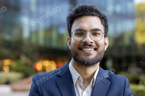Preview: Confident young man in glasses and suit smiling outdoors in urban setting