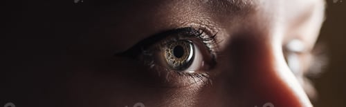Preview: close up view of human eye looking away in darkness, panoramic shot