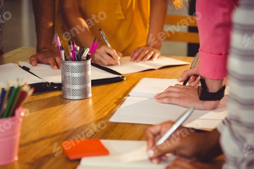 Preview: Mid section of business executives writing in book