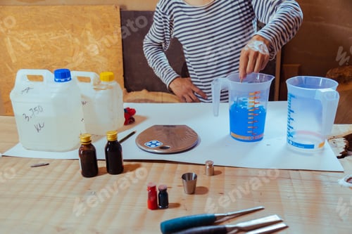 Preview: Closeup carpenter preparing epoxy resin for woodworking and carpentry production