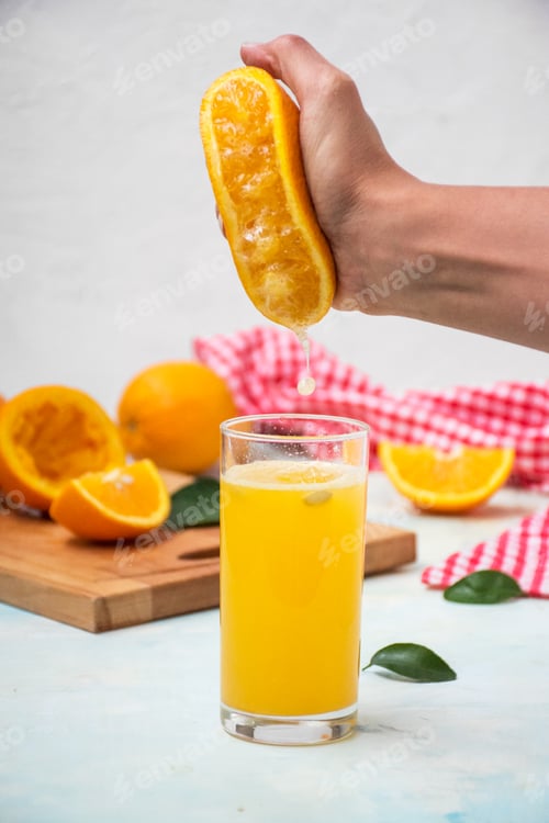 Preview: Man is juicing an orange into a glass on a table
