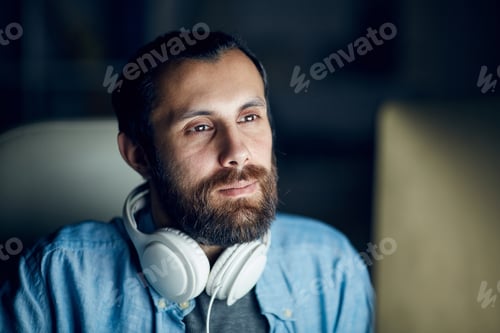 Preview: Man Working with Headphones Around Neck Indoors