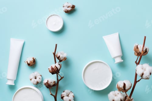 Preview: Fluffy cotton flowers, face cream, body butter on blue background with copy space. Cosmetics, beauty