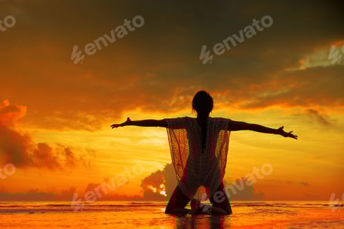 Preview: Silhouette of a young and fit woman on the beach at sunset