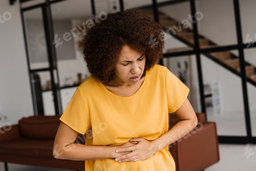 Preview: Woman holds abdomen from pancreatitis and stomach ache at home.