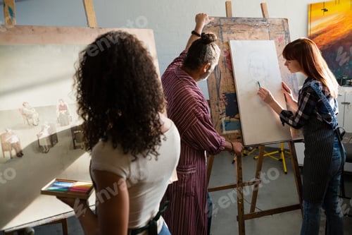 Preview: Rear view of woman painting on canvas while man assisting friend