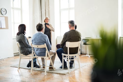 Preview: A woman talking to other people during group therapy.