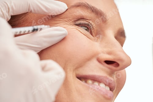 Preview: Beauty procedure. Close up of a beautiful mature woman receiving hyaluronic acid injection by