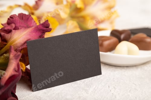 Preview: Black business card with chocolate candies and iris flowers on gray concrete background
