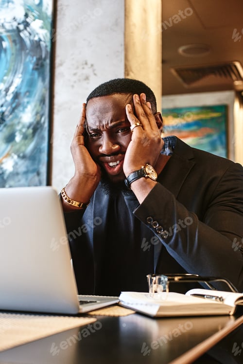 Preview: Designer worry about deadline of new project. Man hold head by two hands and look in laptop with