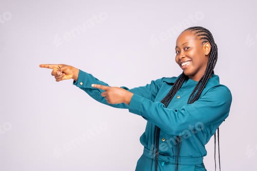 Preview: Young African lady from Nigeria posing wearing a blue jumpsuit pointing to the left with her hands