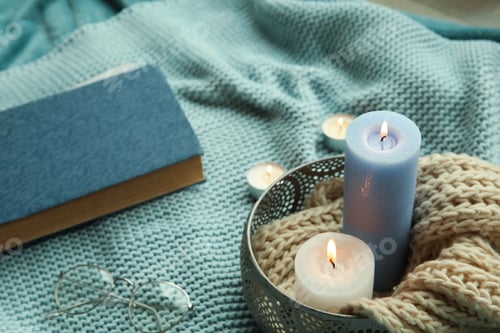 Preview: Beautiful composition with burning candles, eyeglasses and book on fabric