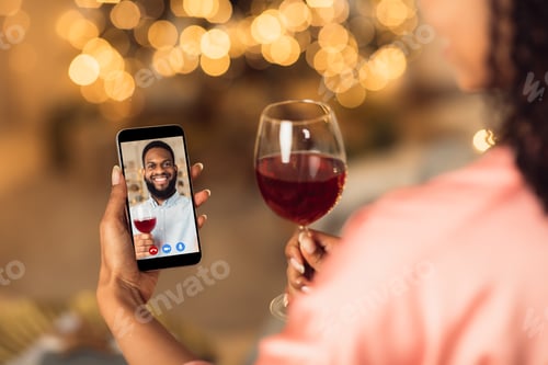 Preview: Black couple having online date on phone, drinking wine