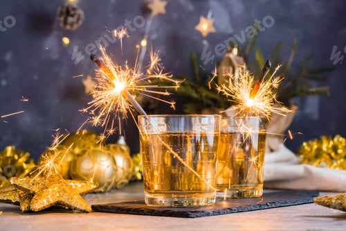 Preview: Burning sparklers in glasses with cocktails on the Christmas table. Gold palette