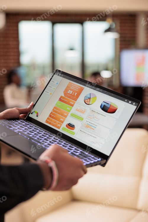 Preview: Man holding laptop with business charts