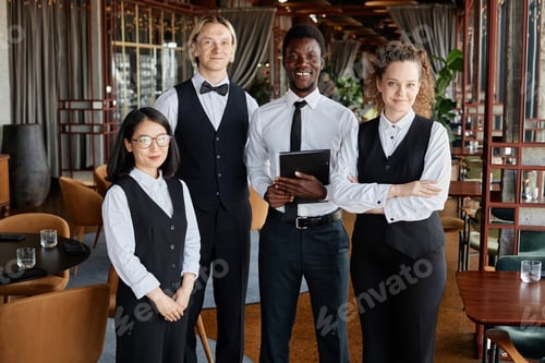 Preview: Restaurant staff with servers wearing classic black and white uniforms smiling