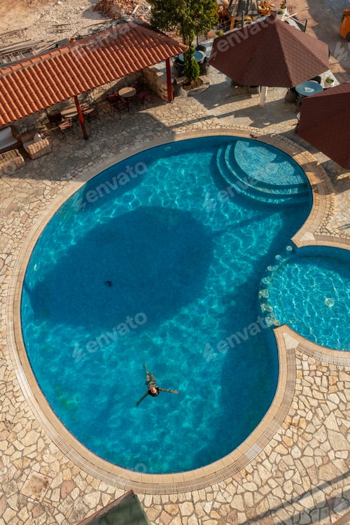 Preview: Aerial shot of a swimming pool with a woman bathing enjoying the summer vacation