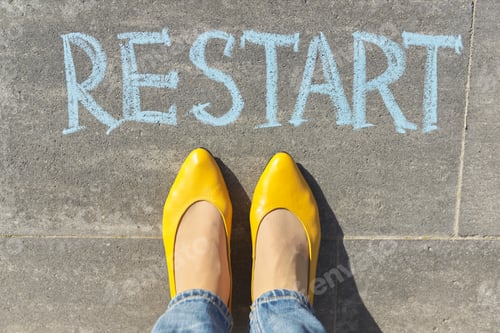 Preview: Restart concept, top view on woman legs and text written in chalk on gray sidewalk