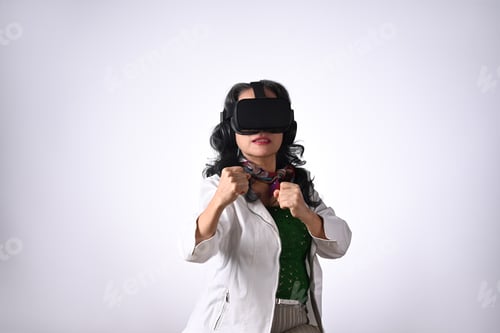 Preview: Senior woman in boxing stance, playing action simulator game in VR headset
