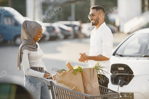 Preview: Multi ethnic couple charge elctric car after shopping