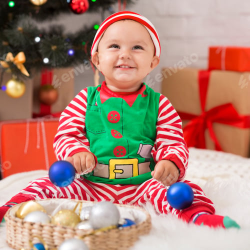 Preview: Happy baby elf with Christmas decorations laughing