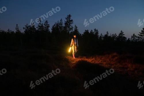 Preview: Young girl walk countryside at night hold led lamp to highlight pathway to camp or car after hiking