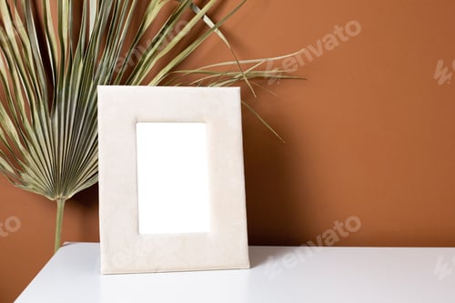 Preview: Beige frame copyspace and dry plant on white table with dark orange wall background, trend design
