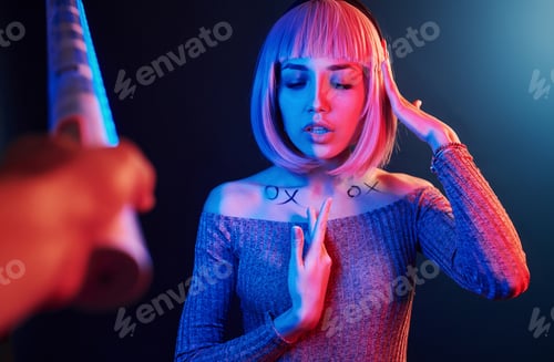 Preview: Portrait of young girl with blond hair in red and blue neon in studio