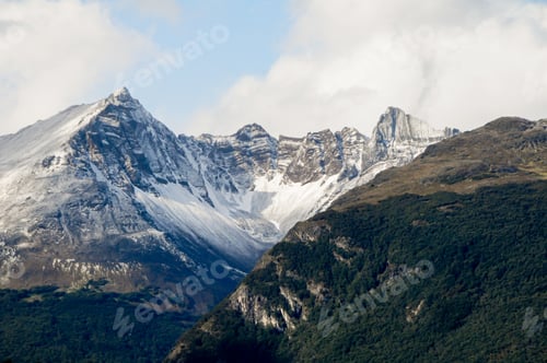 Preview: Mountain PeakMountain peaks covered with snow and hills with grass and vegetation