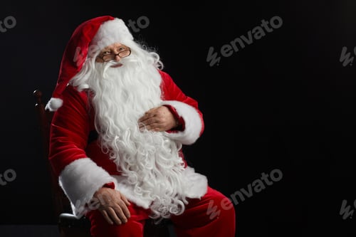Preview: Santa Claus sits on a black background and looks at the camera. Christmas, New Year