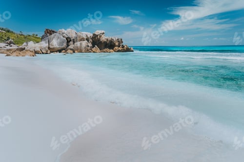 Preview: Wave on pristine blue color lagoon with granite rocks on Anse Coco beach, La Digue Island