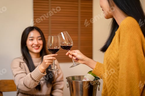 Preview: Young smiling woman drinking and clinking glass of wine to toast