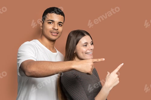 Preview: A charming couple pointing to the right with their hands and smiling at the camera