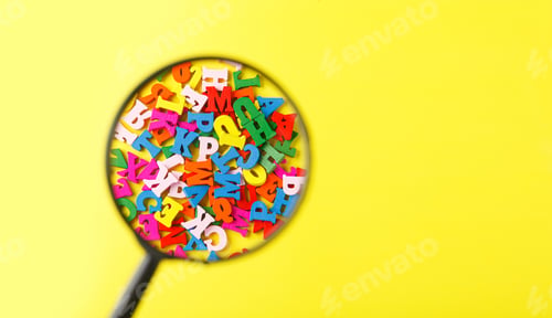 Preview: colored letters of the alphabet with a magnifying glass on a yellow background