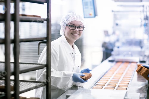 Preview: Factory worker on food production line looking at camera smiling